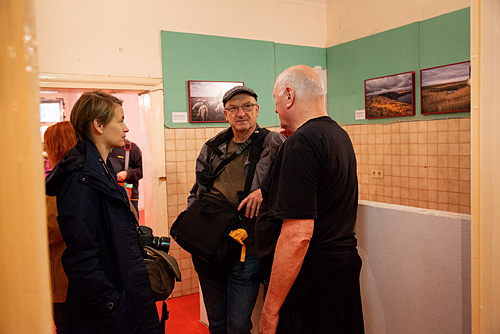 Fotografie Inspirationen. Kursteilnehmer in einem Ausstellungsraum unterhalten sich mit dem Direktor der Ausstellung Lois Lammerhuber.