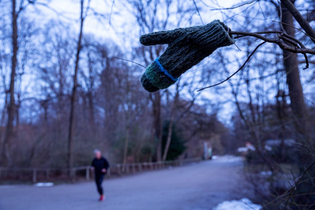 Mann ist im Wald am joggen und auf einem Ast hängt ein Handschuh